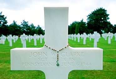 Headstones at a United States Military Cemetery at Utah Beach in Normandy, France.  Flowers have been left beside one of the crosses.