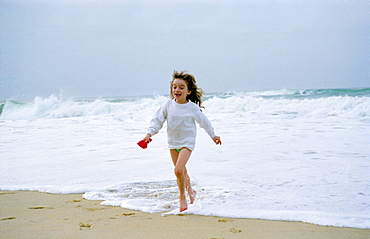 An eight year old girl running out of the sea during a holiday in France