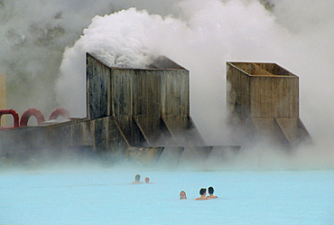 Clouds of steam rise as people swim in the Blue Lagoon thermal pool, Iceland