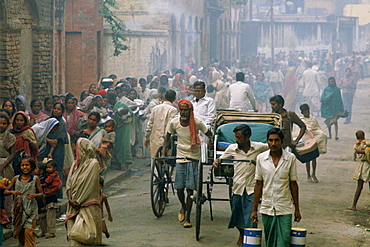 Rickshaws pass as poor people queue for food in the early morning at Mother Teresa's Mission in Calcutta, India.