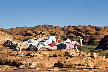 Tourists lie down to photograph King's Canyon, Red Centre, Northern Australia