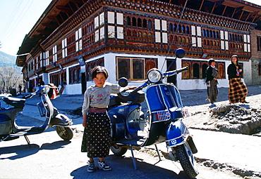 Girl standing by a  scooter, Paro, Bhutan