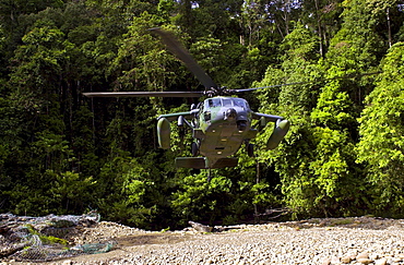 Military helicopter hovers in clearing in Ulu Temburong National Park, Brunei