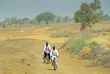 Two men cycling the deserted road to Sebba, Burkina Faso (formerly Upper Volta)