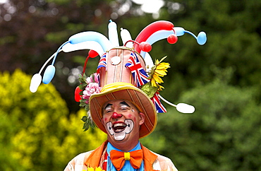 A clown laughing during a community picnic where local groups are providing musical and dance entertainment to celebrate the ethnic diversity of West London at Gunnersbury Park