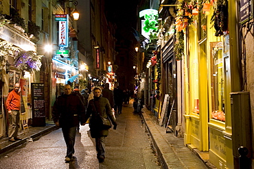 Couple stroll through Rue Gregoire de Tours past shops, near Boulevard St Germain, Left Bank, Paris, France