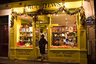 Woman leaves a Parisian newsagents shop in Rue Gregoire de Tours, Paris, France