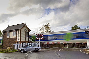 Car waits at railway crossing in Ascott-Under-Wychwood, Oxfordshire, United Kingdom