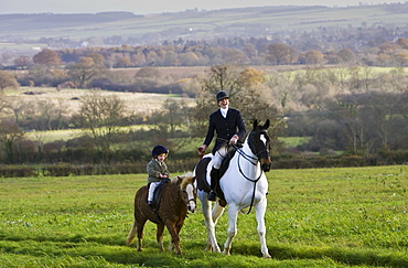 Mother and daughter ride together through rolling hillsides, The Cotswolds, Oxfordshire, United Kingdom