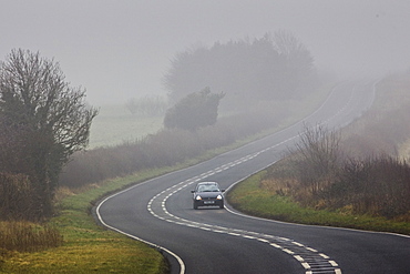 Car drives along foggy road, Oxfordshire,  United Kingdom