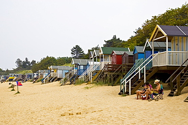 Couple sit outside beach hut in Wells, Norfolk, United Kingdom