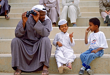 A man and two boys sitting on steps in Kuwait.