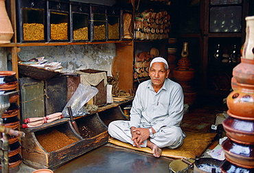 Shopkeeper  sitting cross-legged in his shop selling tobacco, Islamabad, Pakistan