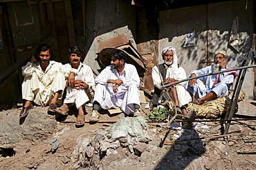 Pakistani men sit together in earthquake devastated village of Pattika, Pakistan