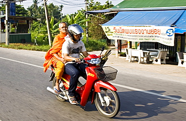 Man and a Buddhist monk travel on a motorcycle, Bangkok, Thailand