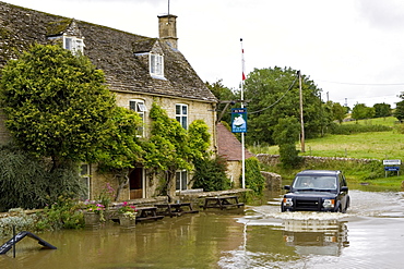 Four wheel drive car drives through flooded road in Swinbrook, Oxfordshire, England, United Kingdom