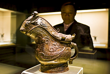 Man looks at Fu Yi Gong wine vessel on display in glass case at the Shanghai Museum, China