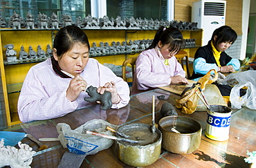 Women make clay figure souvenirs in factory, Xian, China