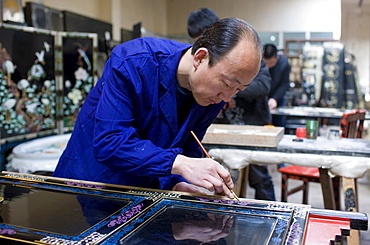 Marquetry craftsman at work on lacquer fire screen at souvenir and furniture factory, Xian, China