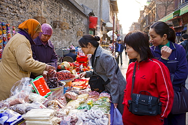 Chinese women selling souvenirs and food at market stall in Moslem district of Xian, China