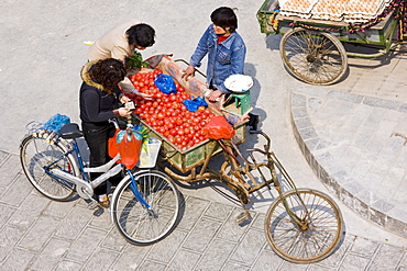 Women buying tomatoes from cart in street market, viewed from the City Wall, Xian, China