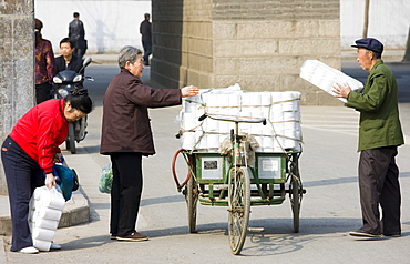 Women buy toilet paper from tradesman from carts in street market by the City Wall, Xian, China