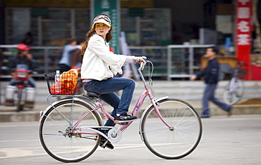 Young woman on a bicycle in Yangshuo street, China