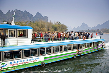 Tourist boat from Guilin Tourism Co. Ltd carries Chinese tourists along Li River between Guilin and Yangshuo, China