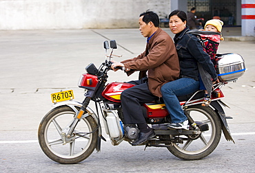 Couple with child on motorbike in Guilin, China. China has a one child family planning policy to reduce population.