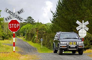 4-wheel drive off road vehicle at railway crossing with traffic signs, North Island, New Zealand