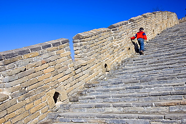 Chinese boy walking up steps of the Great Wall of China at Mutianyu, north of Beijing, China