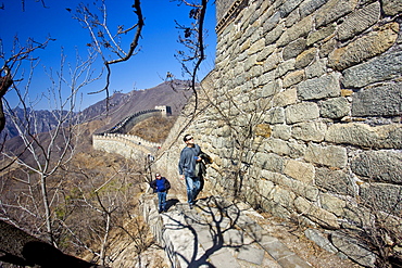 Two men walk along the side of the Great Wall of China at Mutianyu, north of Beijing (formerly Peking), China