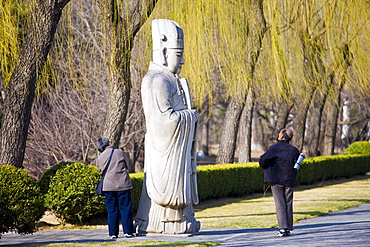 Elderly tourists look at statue of a high civil official, advisor to the emperor, on Spirit Way, Ming Tombs, Beijing, China