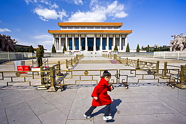 Young girl runs past a soldier outside Mao's Mausoleum, Tian'an Men Square, Beijing, China