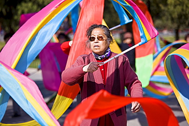 Woman practises tai chi dancing with ribbons in park of the Temple of Heaven, Beijing, China