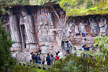 Tourist look at Anicca, God of Destiny holding wheel of life, Dazu rock carvings, Mount Baoding, China