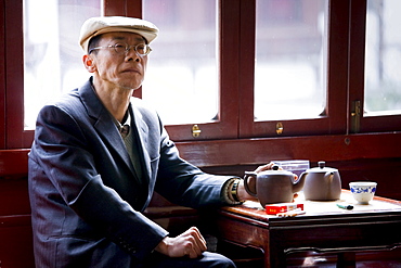 Man drinking tea in the Huxinting Teahouse, Yu Garden Bazaar Market, Shanghai, China