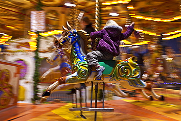 Child enjoying Merry-go-round carousel at Christmas fairground and market, Winter Wonderland, in Hyde Park, London