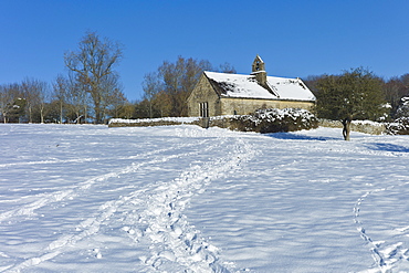 Quaint 13th Century chapel in snow-covered Windrush valley at Widford, The Cotswolds, UK