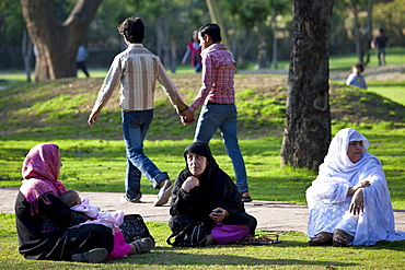 Men holding hands and muslim women with child in gardens at Humayuns Tomb, in New Delhi, India