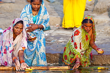 Indian Hindu pilgrims bathing and with prayer candles in The Ganges River at Dashashwamedh Ghat in Holy City of Varanasi, Benares, India