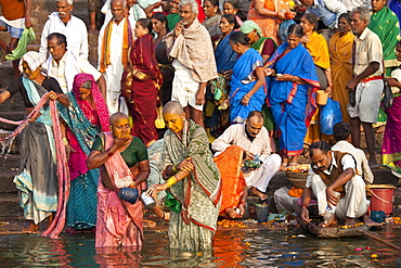 Indian Hindu pilgrims bathing and cleaning teeth in The Ganges River at Dashashwamedh Ghat in Holy City of Varanasi, Benares, India