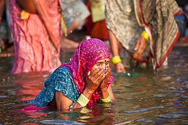 Indian Hindu pilgrim woman bathing in The Ganges River at Dashashwamedh Ghat in Holy City of Varanasi, Benares, India