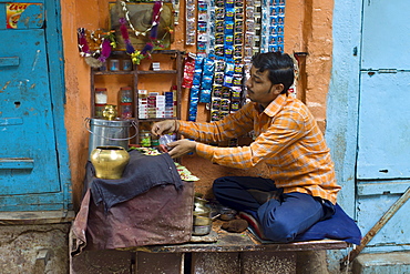 Indian man runs market stall in alleyway in the city of Varanasi, Benares, Northern India