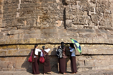 Buddhist visitors applying gold leaf as traditional offering at Dhamakh Stupa at Sarnath ruins near Varanasi, Benares, Northern India