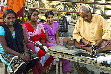 Indian girls in shoe shop with cobbler at work at Sarnath near Varanasi, Benares, Northern India