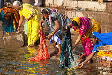 Indian Hindu pilgrims washing clothes and bathing in The Ganges River at Dashashwamedh Ghat in Holy City of Varanasi, India