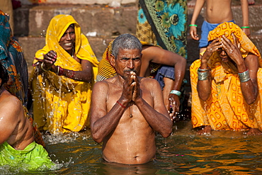 Indian Hindu pilgrims bathing and praying in The Ganges River at Dashashwamedh Ghat in Holy City of Varanasi, Benares, India