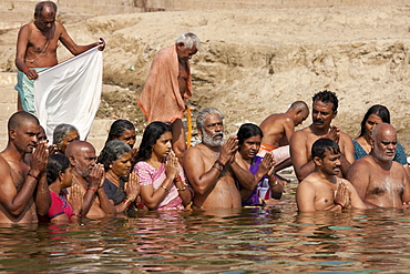 Indian Hindu men and women bathing and praying in the River Ganges by Kshameshwar Ghat in holy city of Varanasi, India