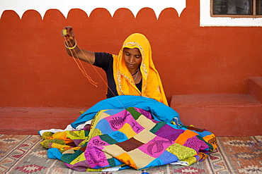 Indian woman sewing textiles at Dastkar women's craft co-operative, the Ranthambore Artisan Project, in Rajasthan, Northern India